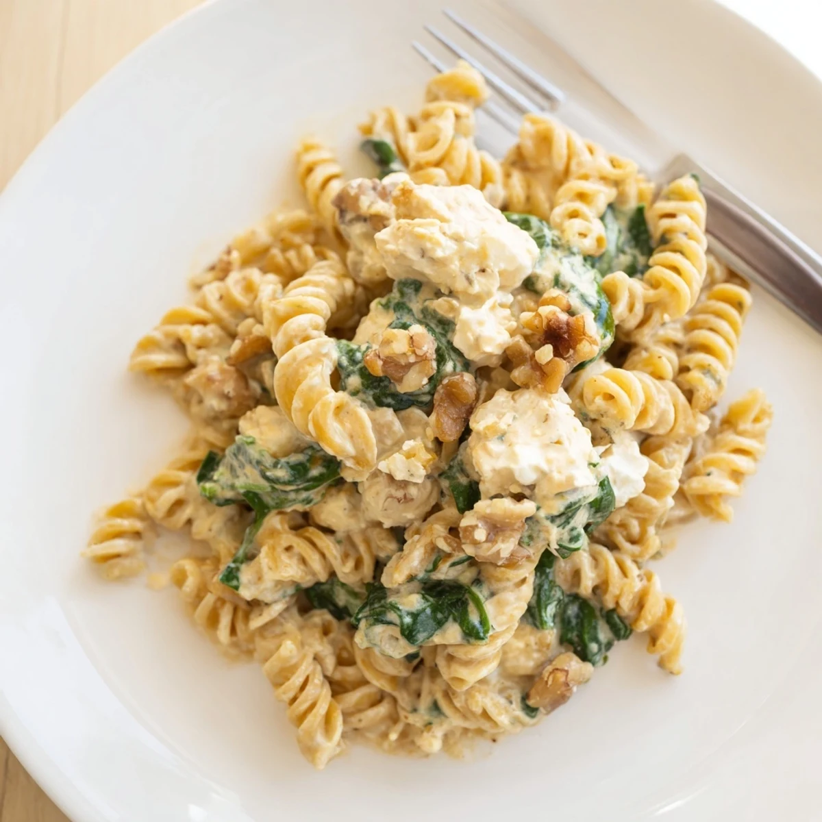 Creamy goat cheese spinach chicken pasta served with crushed walnuts for flavor  