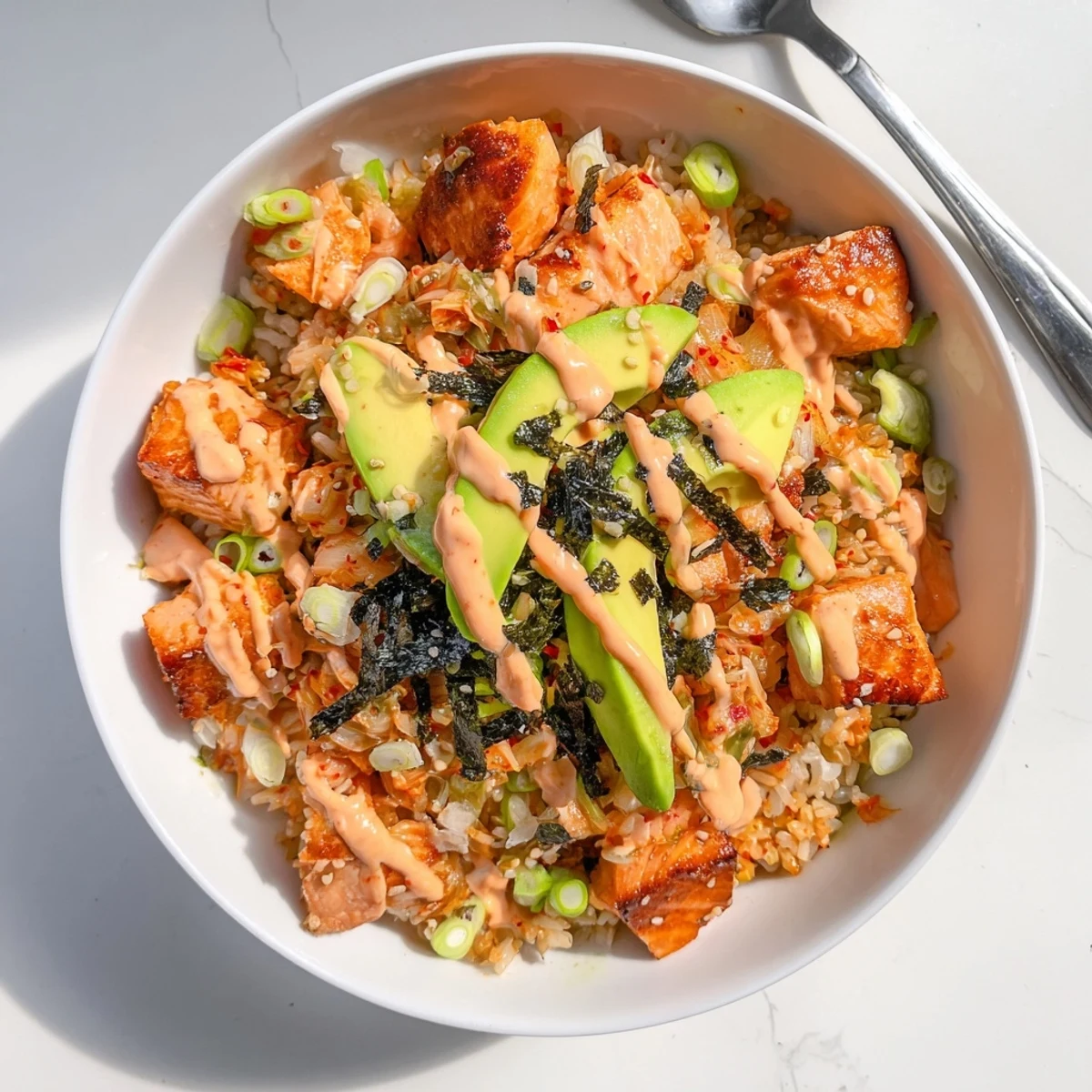 Crispy Salmon Rice Bowl topped with spicy mayo, kimchi, and fresh avocado slices.  