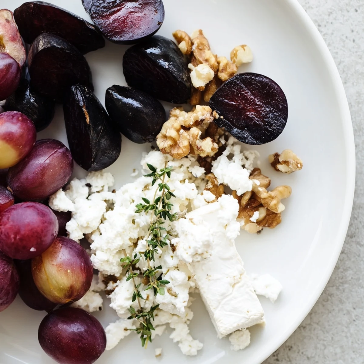 A Midnight Orchard fruit and cheese platter presents vibrant dark fruit with creamy goat cheese.
