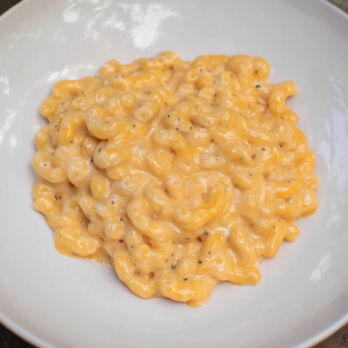 A close-up of creamy Tinis Recession Mac, featuring melted cheddar and American cheese over perfectly cooked macaroni.