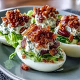 Deviled eggs with tangy filling, bacon crumbles, lettuce, and diced tomatoes in a classic BLT twist.