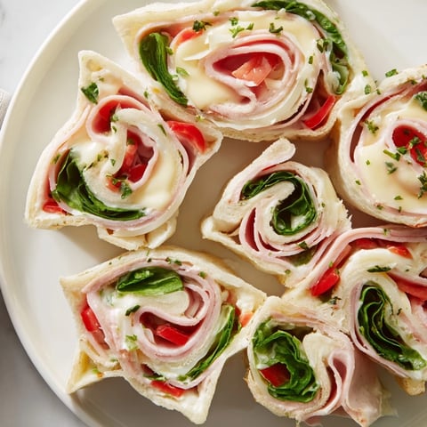 Party Sandwiches: Star-shaped roll-ups showcasing sliced deli meats, cheese, and fresh veggies for a party snack.
