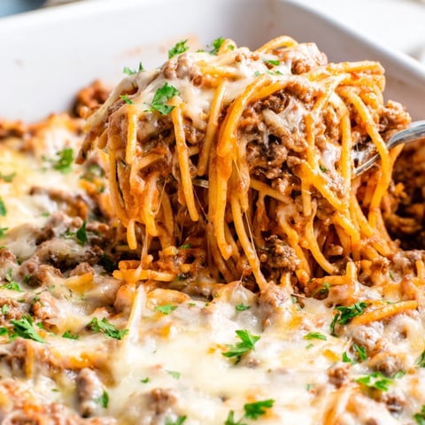 A bubbly, golden Tinis Baked Spaghetti casserole, ready to serve with a garnish of fresh parsley.