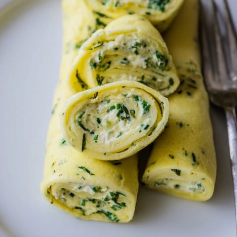 Close-up of rolled Ricotta Herb Omelette showing the cheese filling beside fresh greens.
