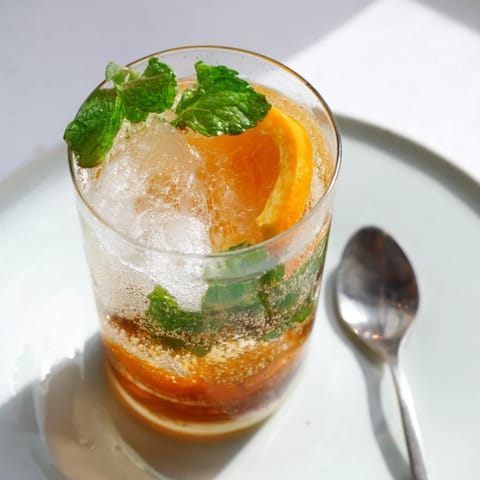 Homemade probiotic soda mocktail garnished with orange slices and fresh mint leaves.  