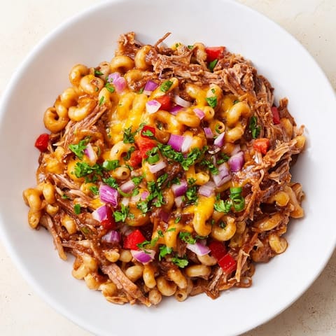 A close-up of a bubbling BBQ Rib Macaroni Skillet, highlighting tender rib meat and macaroni.