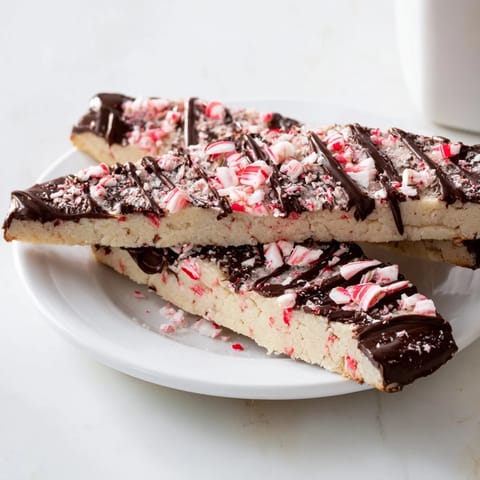 Close-up of buttery, crumbly chocolate peppermint shortbread wedges with a peppermint candy sprinkle.