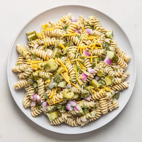 A vibrant bowl of Dill Pickle Pasta Salad with crunchy pickles, ideal for a summer picnic.