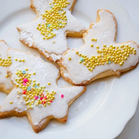 Golden-edged Biscuits Anges de Noël, angel-shaped cookies, beautifully decorated with icing and sprinkles.