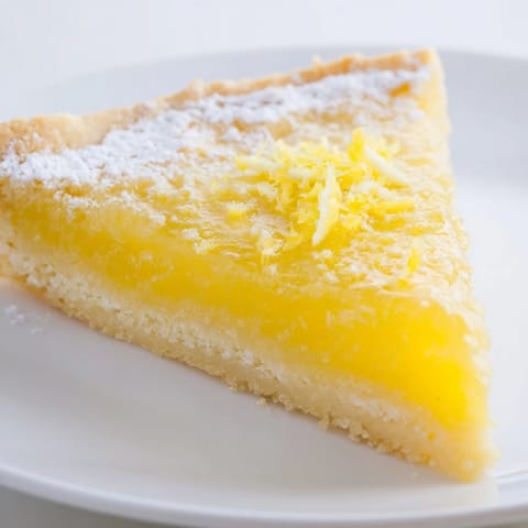 Freshly baked lemon bars, showcasing a buttery shortbread crust and a bright, citrus filling.