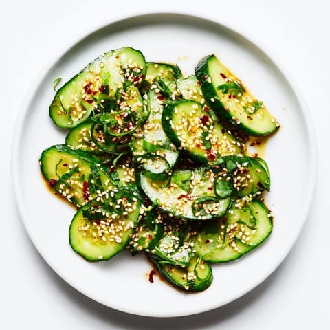 A close-up of the Zesty Shake Cucumber Salad, with glistening cucumbers and sesame seeds sprinkled on top.