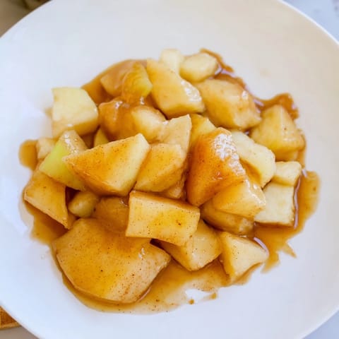 A warm bowl of Slow Cooker Stewed Apples, glistening and infused with cinnamon spice.