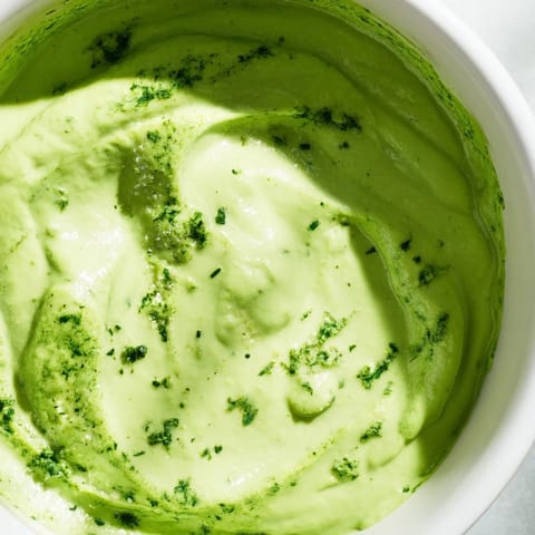 A visually appealing swirl of creamy Green Goddess Dressing, perfect for dipping fresh vegetables.