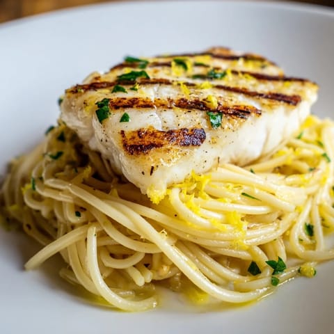 A vibrant plate of Lemon Bass Pasta with flaky white fish, garlic, and parmesan, ready for dinner.
