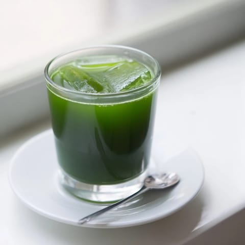 The bright green Cabbage and Kale Detox Juice shines in a mason jar, showcasing the blended texture of cabbage and celery with a hint of fresh ginger and lemon zest.  