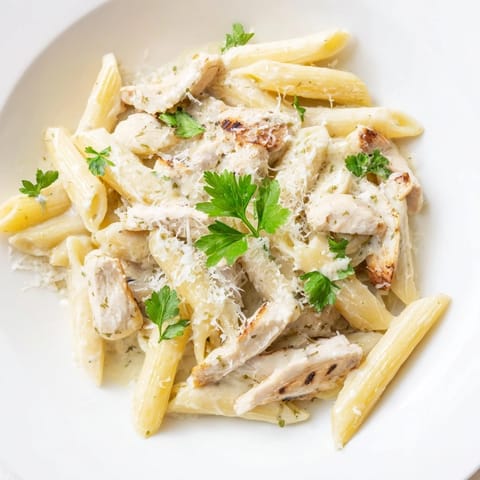 Hearty bowl of Roasted Garlic Chicken Penne features oven-roasted chicken, silky garlic cream sauce, and a sprinkle of Parmesan.