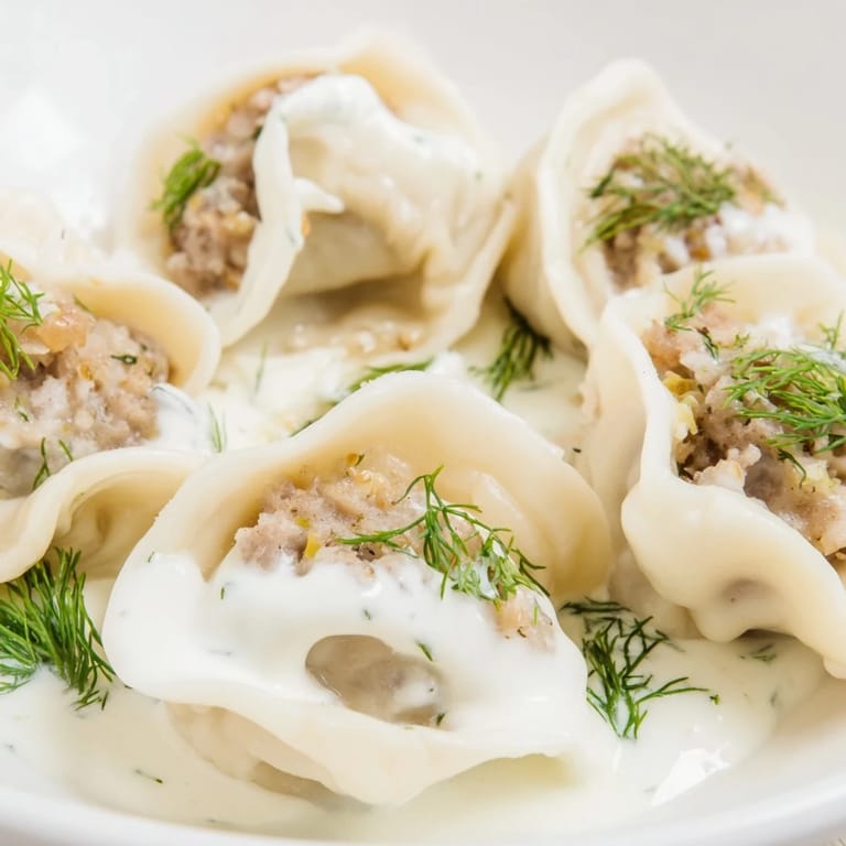 A close-up of delicious Russian Pelmeni, a classic comfort food, ready to be enjoyed with dill.