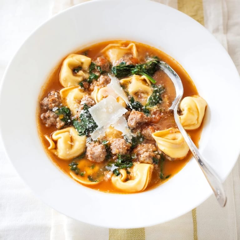 A comforting Tuscan Tortellini Soup simmering in a pot with tomato broth and cheese tortellini.