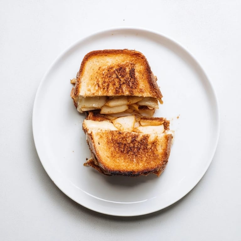 A comforting Smoked Gouda & Apple Grilled Cheese, sliced to show the steamy interior, paired with a bowl of creamy tomato soup.