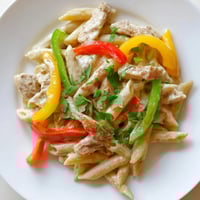 Steamy skillet of Fajita Chicken Pasta, with colorful bell peppers and melted cheese sauce.