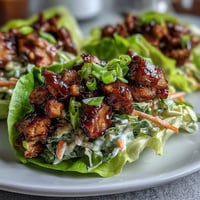 High-protein BBQ chicken lettuce wraps with slaw, featuring tender chicken in smoky sauce, crisp lettuce, and crunchy cabbage slaw for a healthy, satisfying meal.