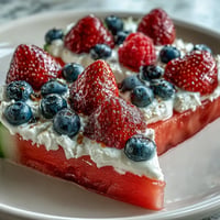 Festive 4th of July Watermelon Pizza crowned with fresh berries and sweet cream.